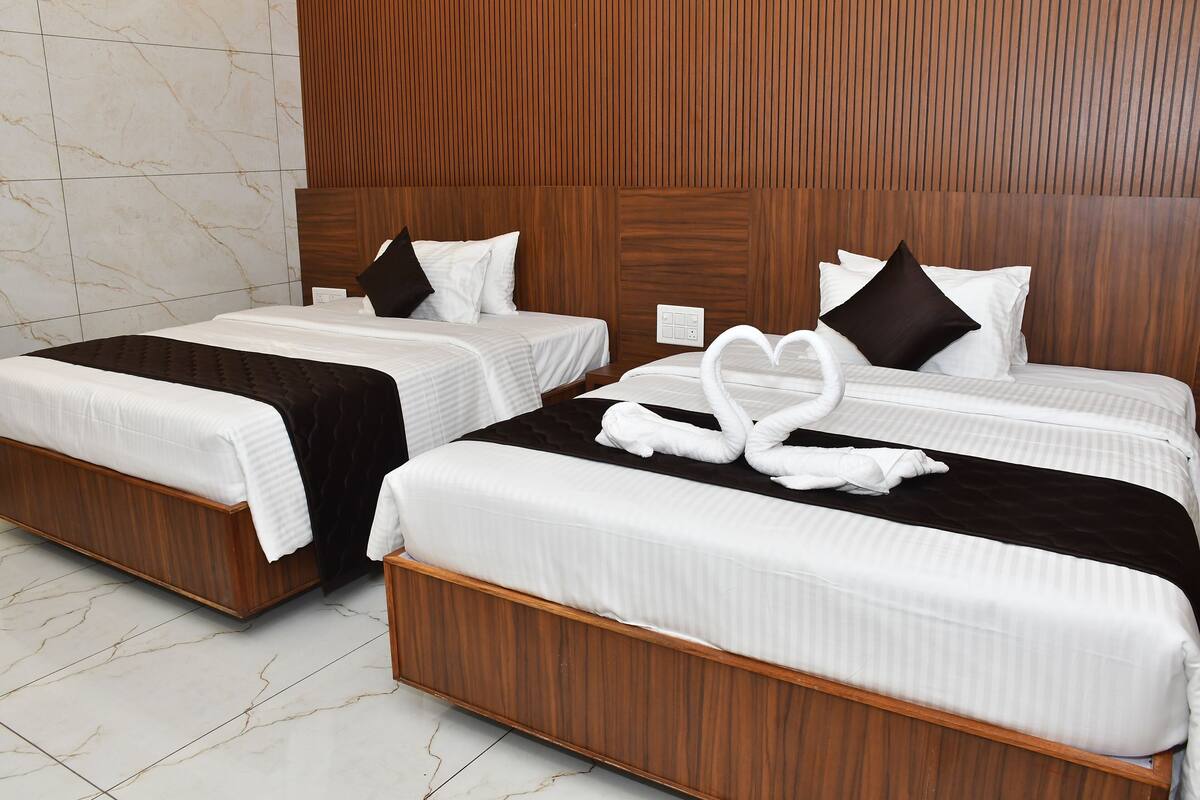 A hotel room with two beds, wooden headboards, marble walls, and a heart-shaped towel decoration.