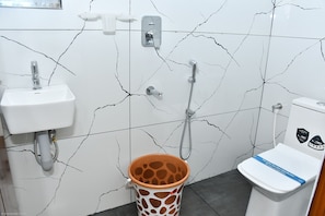 A bathroom with a white sink, a toilet, and a shower. - Vasantham Residency (Rameshwaram)