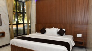 A hotel room with a large bed, wooden headboard, a window with curtains, and a marble floor. - Vasantham Residency (Rameshwaram)