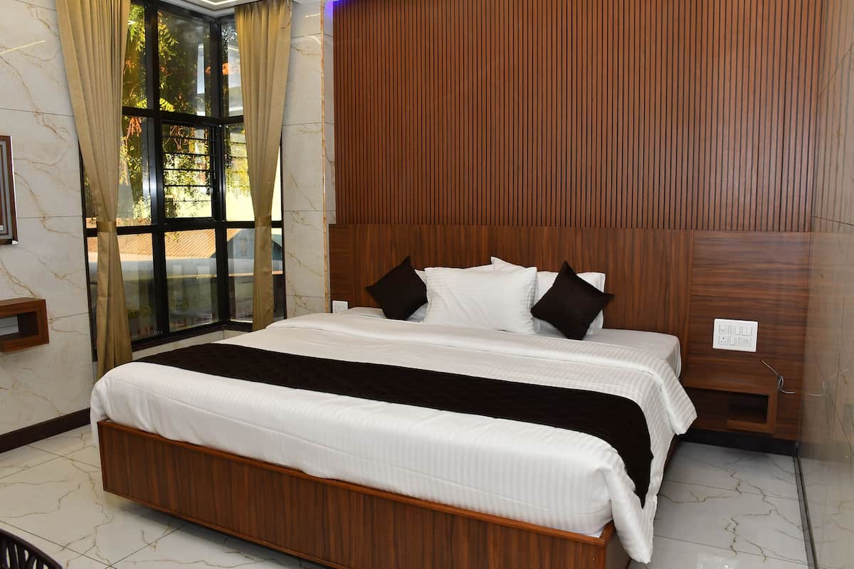 A hotel room with a large bed, wooden headboard, a window with curtains, and a marble floor.