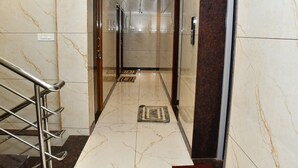 A hallway with marble flooring, a handrail, and a door at the end. - Vasantham Residency (Rameshwaram)
