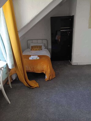 Een slaapkamer met een bed, een nachtkastje, een stoel en een kledingkast.