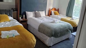 Ein Hotelzimmer mit zwei Betten, einem Spiegel, einem Nachttisch und einem Fenster mit Vorhängen.