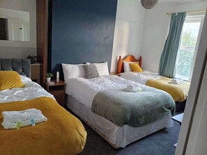 A hotel room with two beds, a mirror, a nightstand, and a window with curtains. - Apt - Sleeps 10 - Parking - Ideal for Contractors (Gateshead)