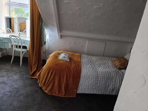 Een slaapkamer met een bed, een bureau en een stoel.