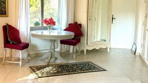A room with a round table, two chairs, a mirror, and a window with curtains. - Sweet Pea sunny cottage in Vence with pool garden private parking (Vence)