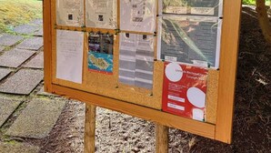 Een prikbord met verschillende informatieposters, waaronder kaarten en veiligheidsvoorschriften.