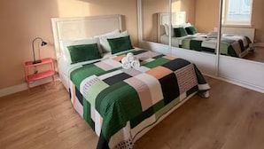 A bedroom with a bed, a mirror, and a nightstand.