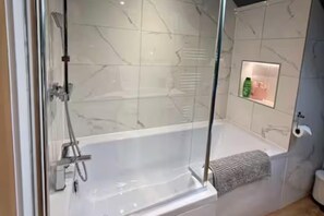 A glass-enclosed shower with a marble wall, a built-in shelf with toiletries, and a towel rack. - 5 Bed House/sleeps10/free Parking/pets/city Centre (Edinburgh)