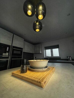 A modern kitchen with a wooden cutting board, a bowl, and a pepper grinder. - 5 Bed House/sleeps10/free Parking/pets/city Centre (Edinburgh)