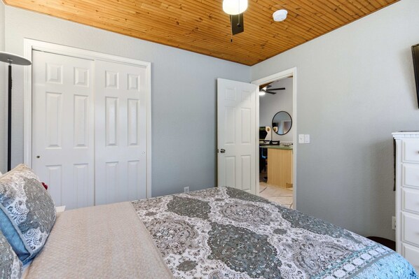 Une chambre à coucher avec un lit, deux portes, un luminaire au plafond et un miroir.