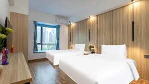 Une chambre d’hôtel avec deux lits, un panneau mural en bois, une fenêtre donnant sur un beau paysage et un bureau agrémenté d’un vase de fleurs.