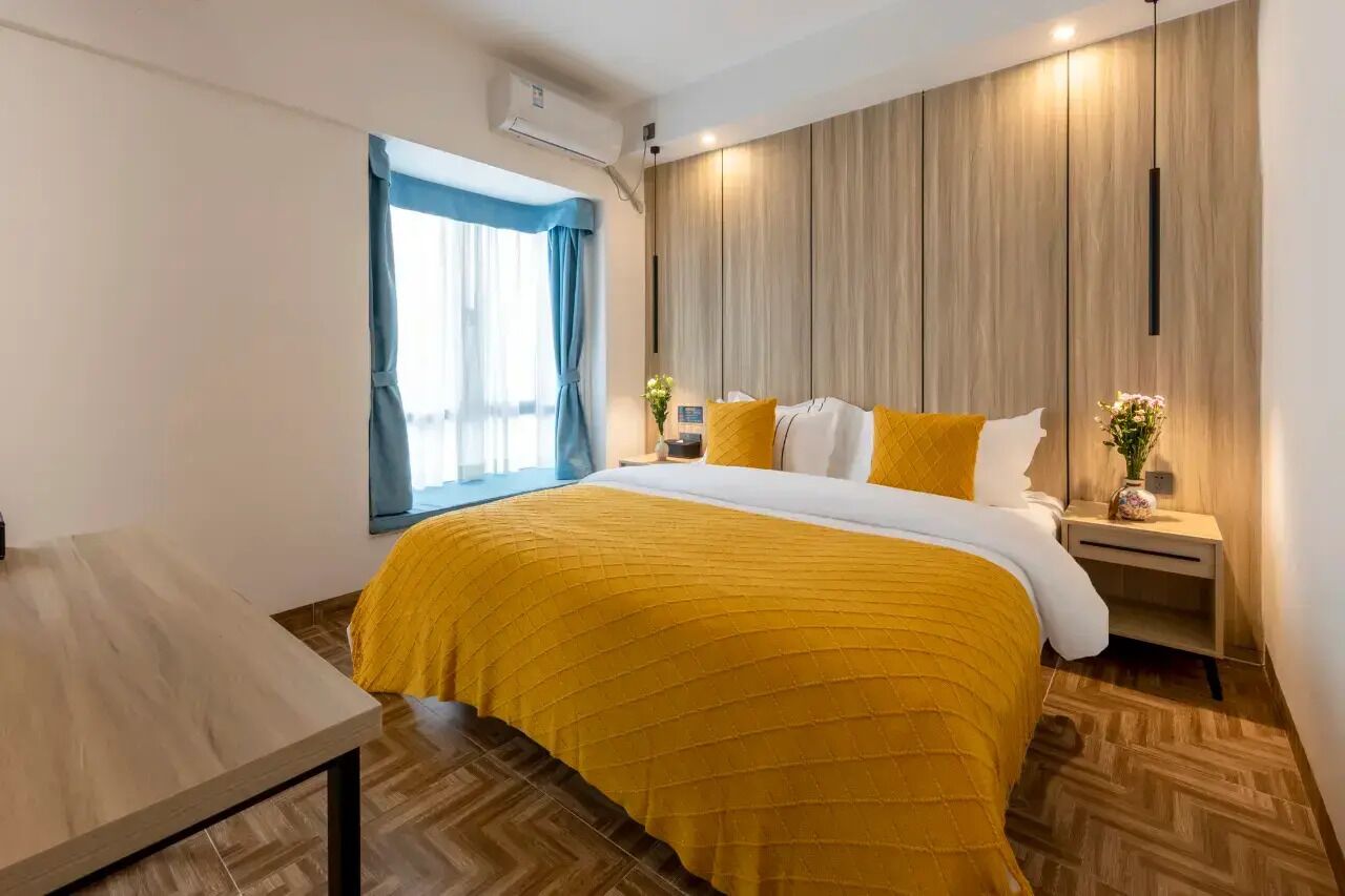 Una habitación de hotel moderna con cama, mesita de noche y ventana con cortinas.