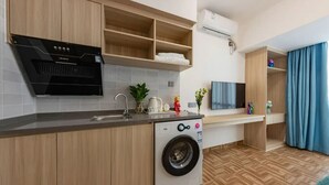 Une cuisine moderne équipée d’un lave-linge intégré, de meubles en bois, d’un four à micro-ondes et d’un téléviseur.