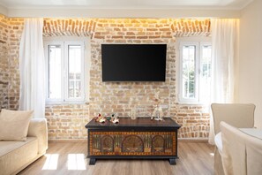 Ein Wohnzimmer mit Backsteinwand, Flachbildfernseher, Holzschrank und Sofa.
