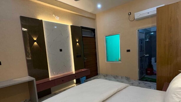 Una camera da letto con un letto, una ventola a soffitto, un condizionatore d'aria a parete e una porta che dà su un bagno.