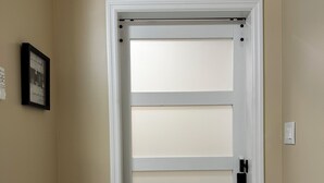 Una puerta con un panel de vidrio esmerilado, un marco blanco y un picaporte negro.