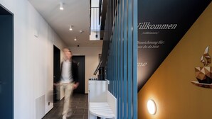 Un intérieur moderne avec un escalier, un comptoir d’accueil et un mur orné d’une inscription de bienvenue.