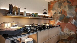 Un buffet proposant une variété de plats et d’accompagnements, un coin café et un mur décoré d’un motif floral.
