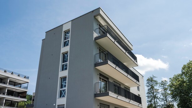 Un immeuble à plusieurs étages, doté de balcons, de grandes fenêtres et d’un toit plat.
