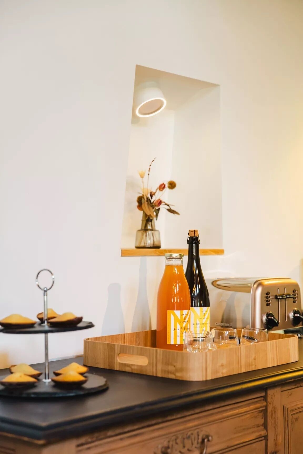 A kitchen counter with a bottle of juice, a bottle of wine, a toaster, and a tray with food items.