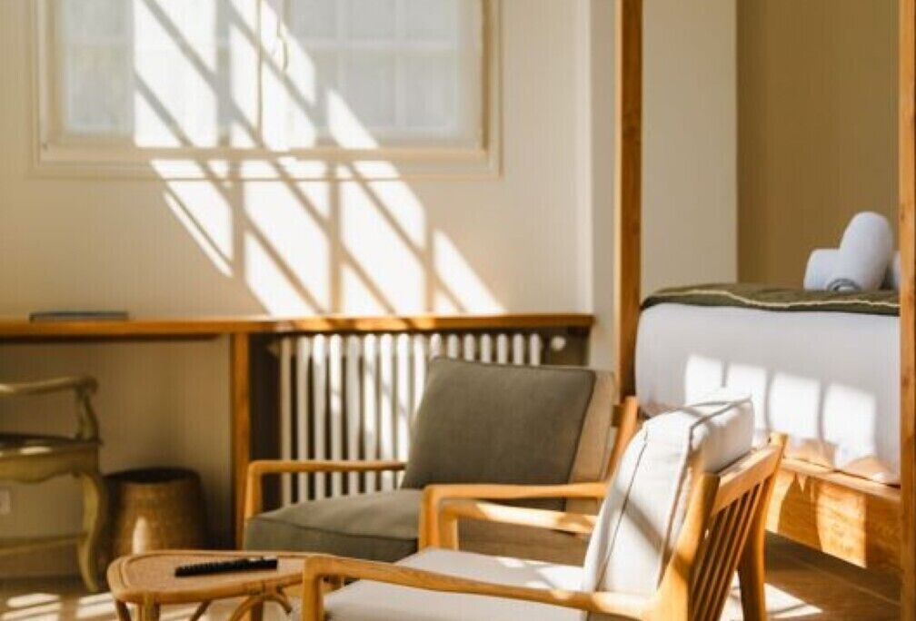 A room with a bed, a chair, a small table, and a radiator.