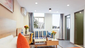 A hotel room with a bed, a sofa, a coffee table, and a window with curtains. - SHENZHEN CHENGBANG LIGHT LUXURY APARTMENTS (Shenzhen)