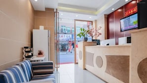 A hotel reception area with a sofa, a reception desk, a television, and a plant. - SHENZHEN CHENGBANG LIGHT LUXURY APARTMENTS (Shenzhen)