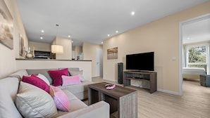 Una sala de estar moderna con sofá, mesa de centro, televisor y un comedor con mesa y sillas.