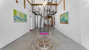 Un pasillo con una escalera, dos cuadros en las paredes y un diseño de piso con forma de brújula.