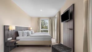 Una habitación de hotel moderna con cama, lámparas de noche, televisor y ventana con cortinas.