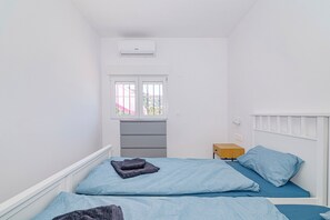 A small, white room with two beds, a window, a radiator, and a bedside table. - Newly renovated villa near the beach with a private... Pool, panoramic terrace, and 4 bedrooms (Velilla-Taramay)
