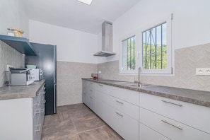 A modern kitchen with a built-in oven, stainless steel appliances, a window with a view, and a grey tiled backsplash. - Newly renovated villa near the beach with a private... Pool, panoramic terrace, and 4 bedrooms (Velilla-Taramay)