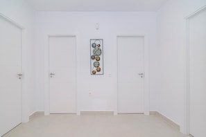 Ein Flur mit zwei weißen Türen, einem Lichtschalter und einem an der Wand befestigten Kunstwerk.