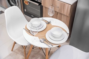 A dining table with white chairs, a placemat, and a glass of water. - Free housekeeping visits during your stay - StayShort - Cozy Studio in Sports City that Sleeps 3 (Sports City)