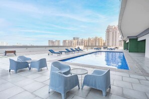 A rooftop pool area with lounge chairs and a bench, surrounded by high-rise buildings. - StayShort - Cozy Studio in Sports City that Sleeps 3 (Sports City)