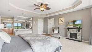 A bedroom with a bed, a chair, a fireplace, and a television. - Sunset Ridge Private Patio (Lake Ozark)