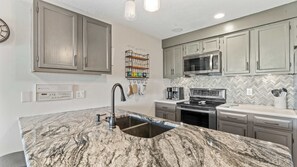 A kitchen with granite countertops, stainless steel appliances, and light gray cabinetry. - Sunset Ridge Private Patio (Lake Ozark)