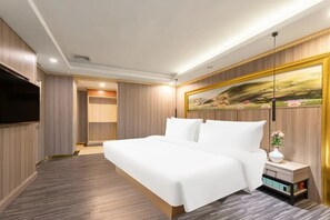 A modern hotel room with a large bed, a flat-screen TV, a painting on the wall, and a nightstand with a vase of flowers. - City-state apartments - Niu Hu Subway (Shenzhen)