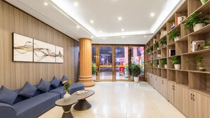Eine moderne Lobby mit Sofa, Couchtisch, Bücherregal und einem großen Fenster.