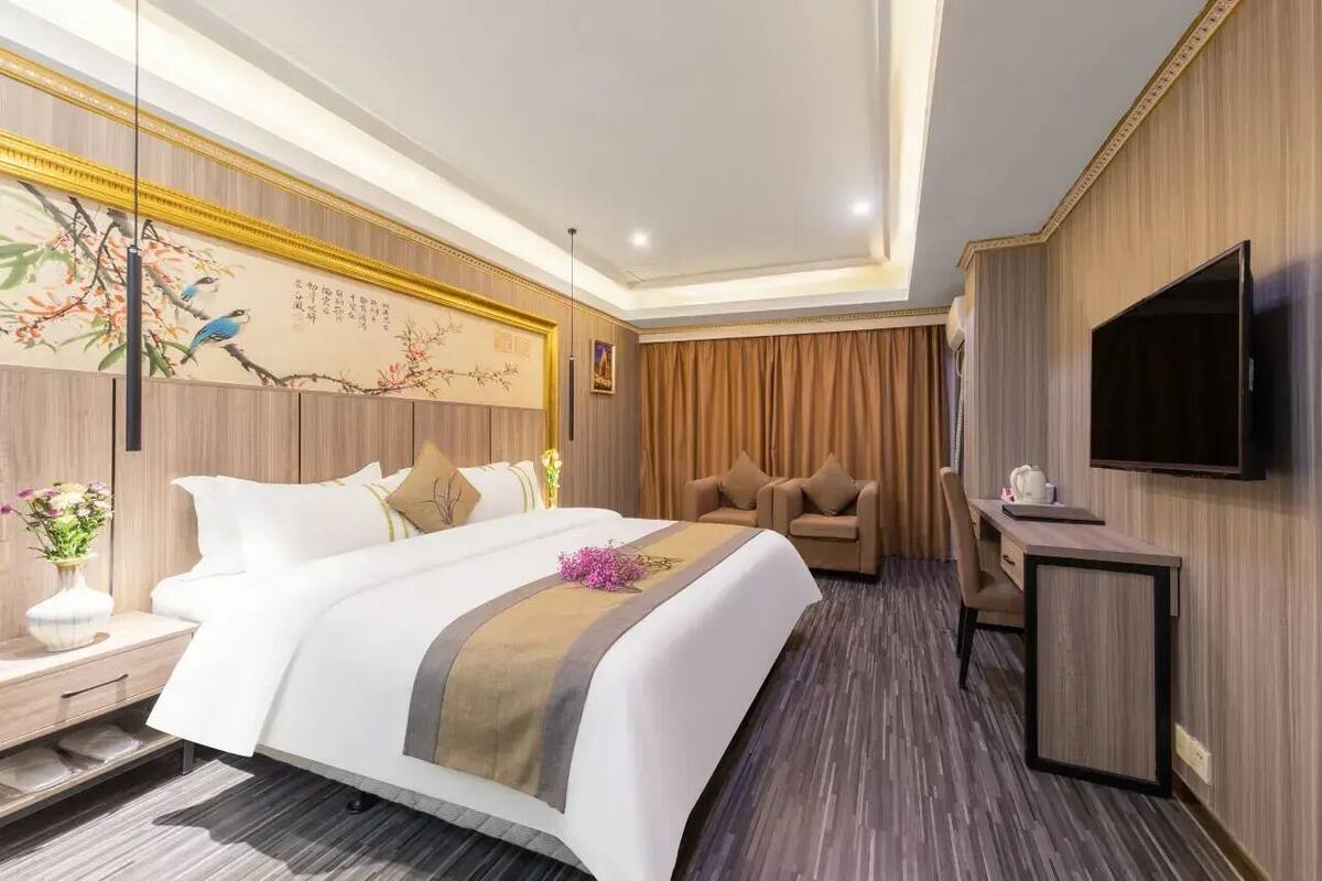 Una habitación de hotel con cama, sofá, escritorio y televisor.