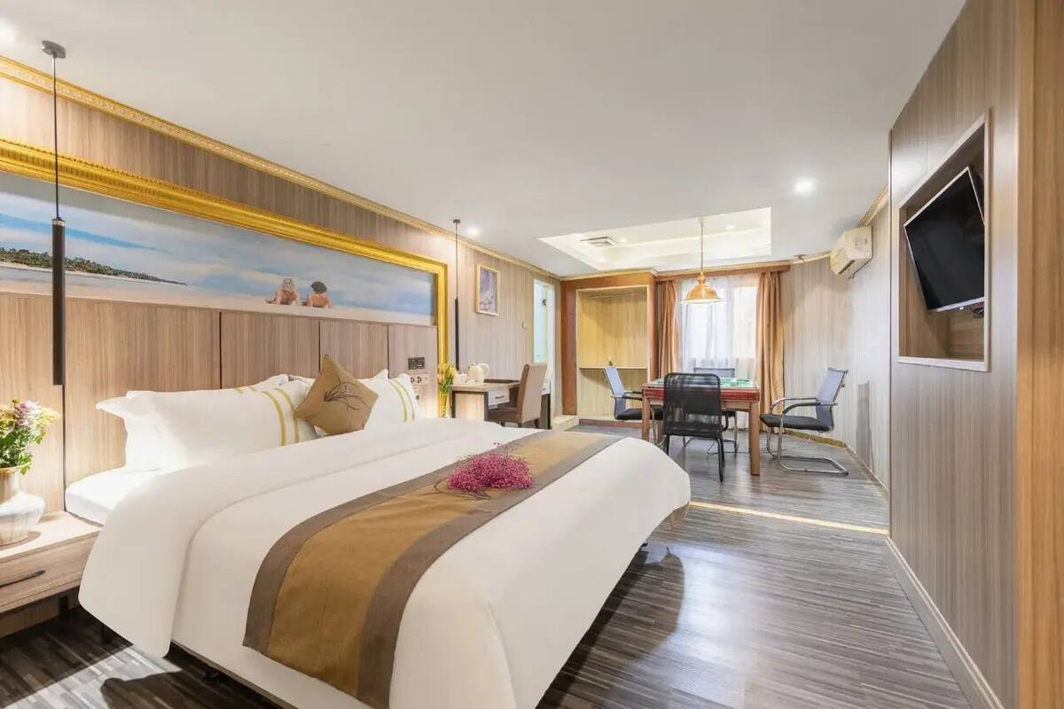 Habitación de hotel con una cama grande, un escritorio, una silla, un televisor y un cuadro en la pared.