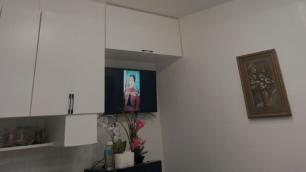 Quarto com televisão de tela plana fixada na parede, teto com iluminação embutida e quadro pendurado na parede.