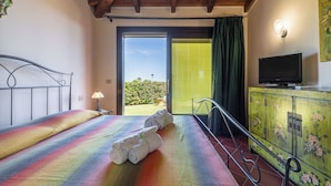 Een slaapkamer met een bed, een televisie, een raam met uitzicht en een balkon.