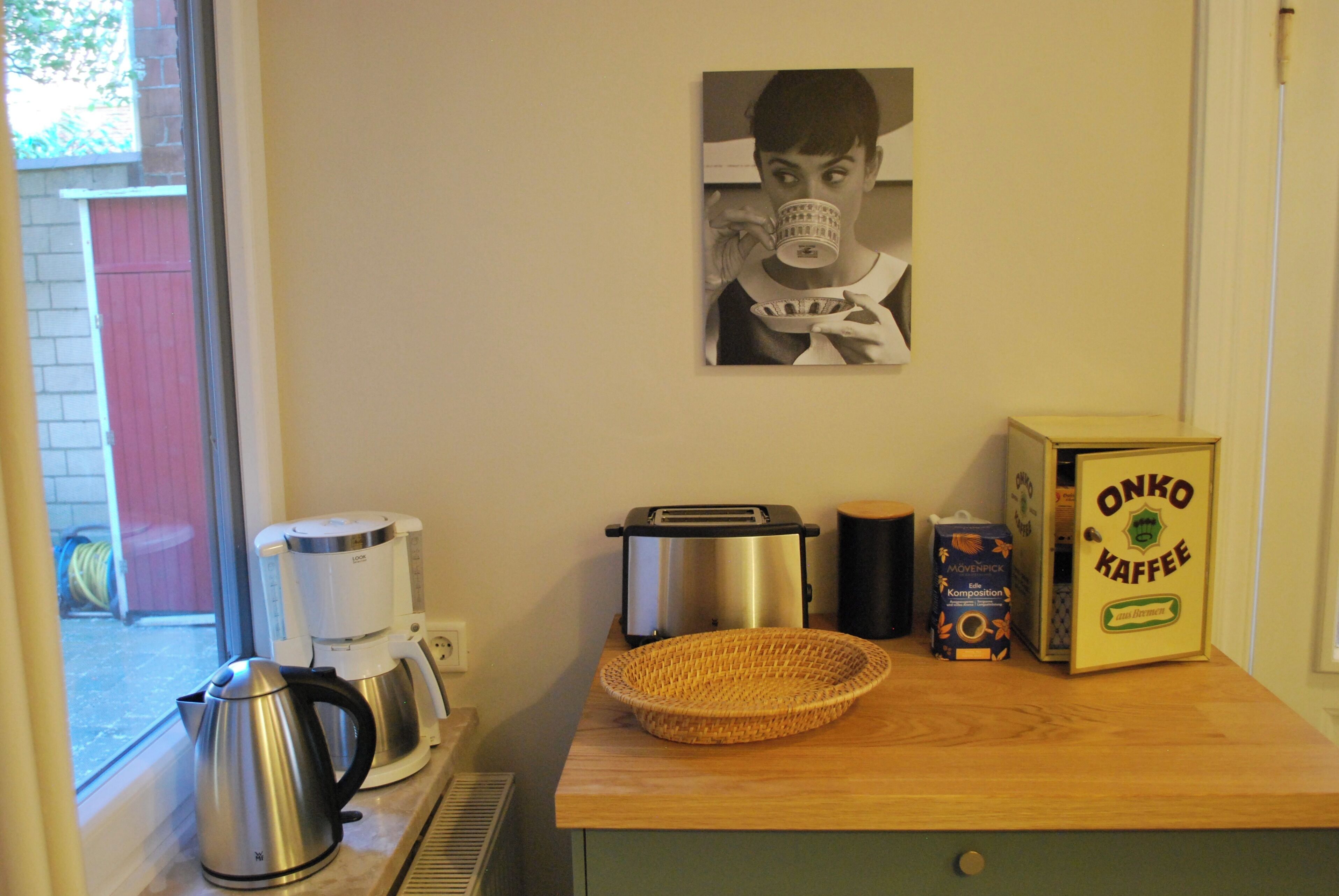 A kitchenette with a coffee maker, toaster, and a basket on the counter.