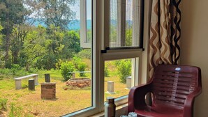 A room with a view of a cemetery, a table with a water bottle, and two plastic chairs.
