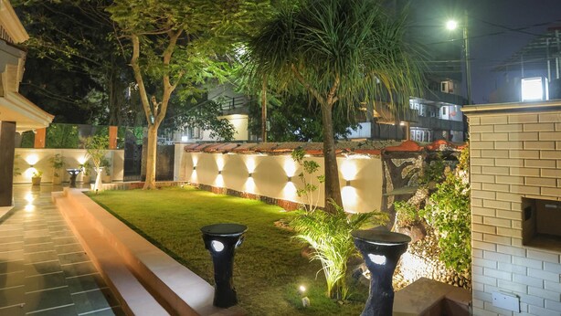Un espacio al aire libre de noche con un camino pavimentado, un pequeño césped y una construcción de ladrillo.