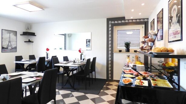 Zona pranzo con tavoli e sedie, un buffet con diversi cibi e una parete con quadri incorniciati.