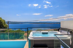 A hot tub with a glass railing, overlooking a body of water and distant landscape. - Dramalj luxury villa - pool, whirlpool & sea view (Dramalj)