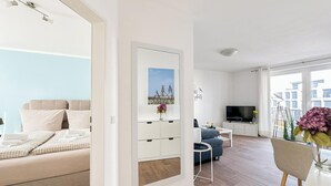 A modern living room with a sofa, a television, and a dining area with a table and chairs. - Vacation apartment Marina Liebe directly in the City Marina Cuxhaven (Cuxhaven)